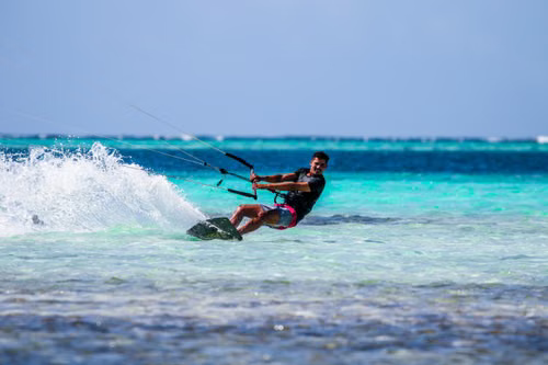 Persona practicando kitesurf en mar turquesa
